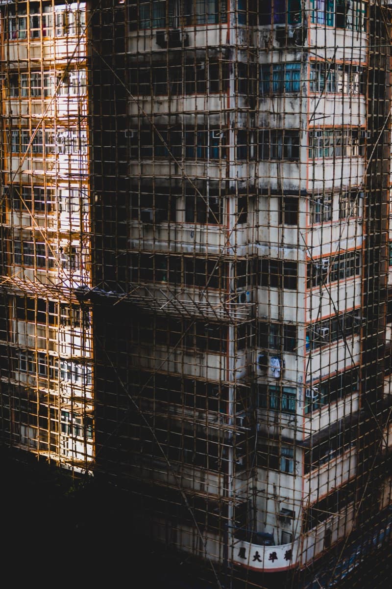 Residential building covered in traditional bamboo scaffolding with street-level signage