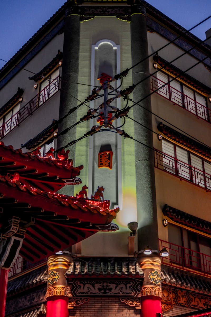 Ornate Chinese temple with dragon-adorned roof and illuminated tower at night in Yokohama
