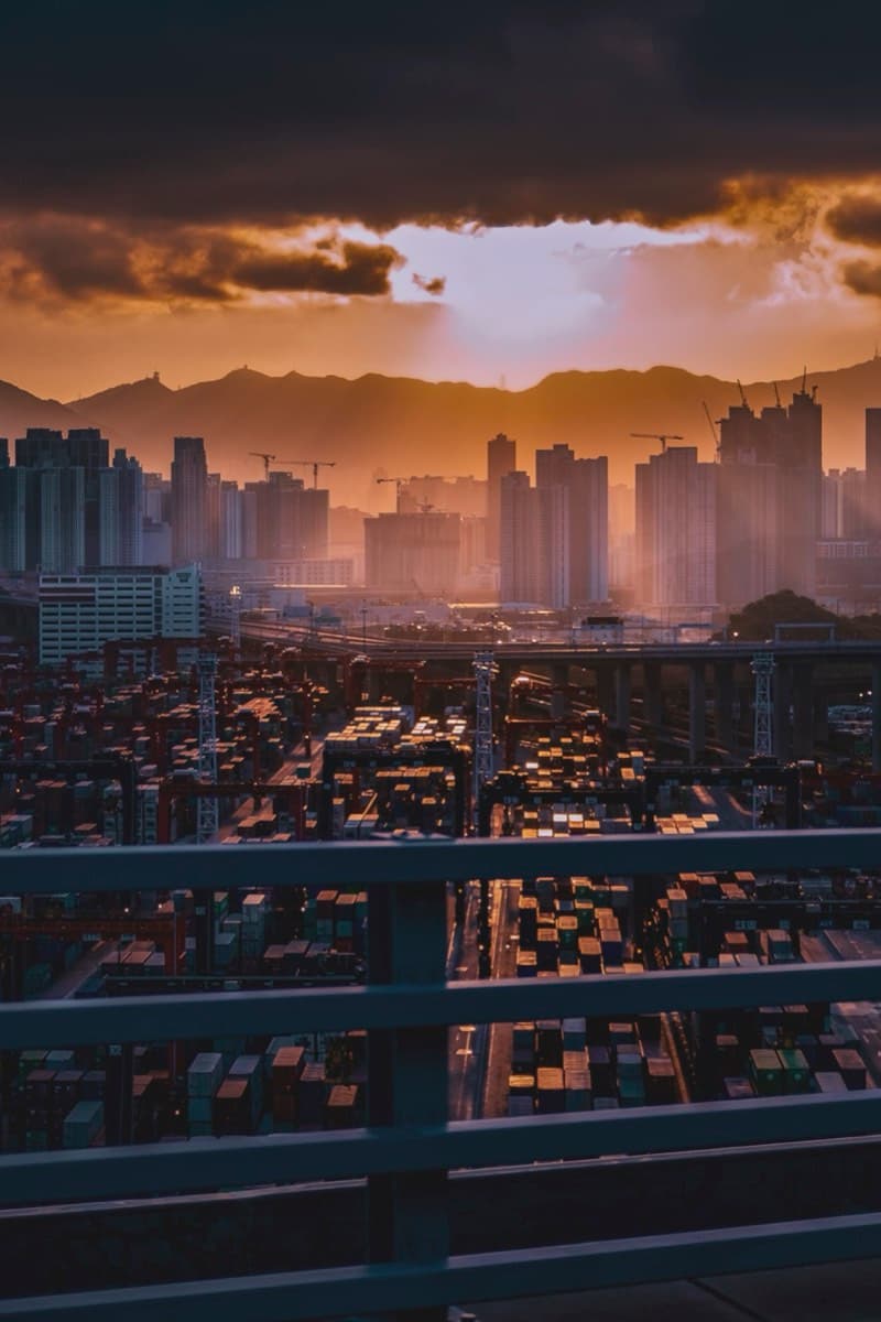 Golden sunrise over an industrial container yard with city skyline and mountains behind