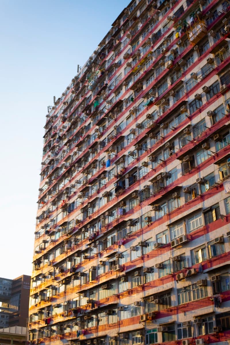 Dense apartment building facade lit by golden hour sun with air conditioning units and laundry