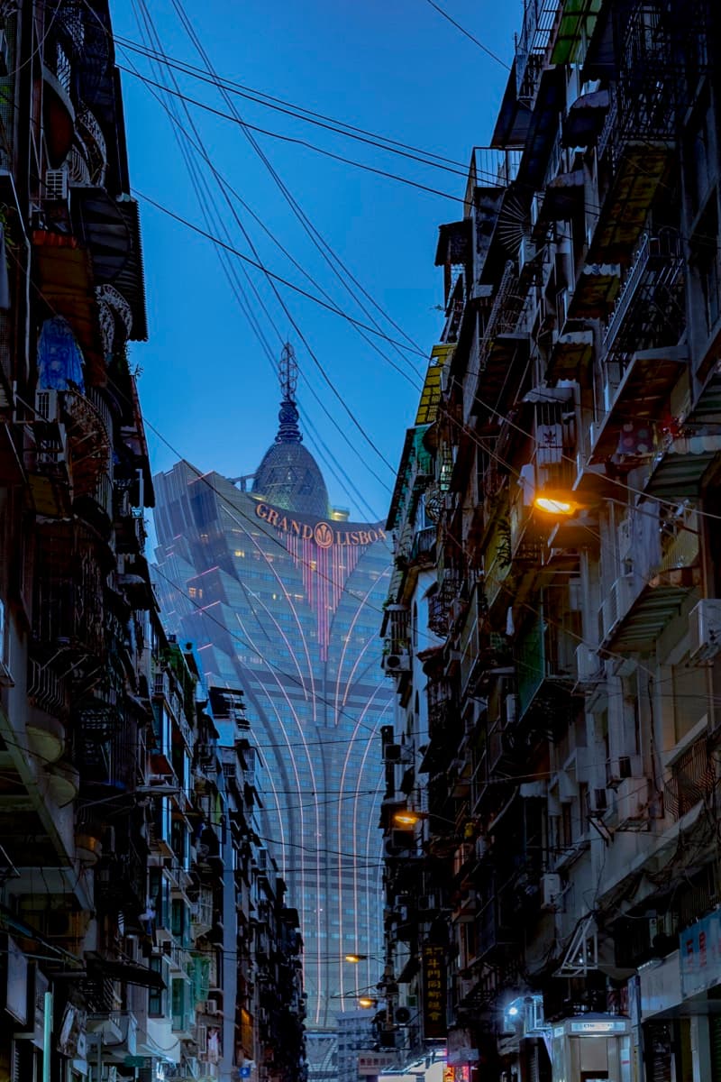 Grand Lisboa casino tower at dusk seen through a narrow alley with old tenement buildings