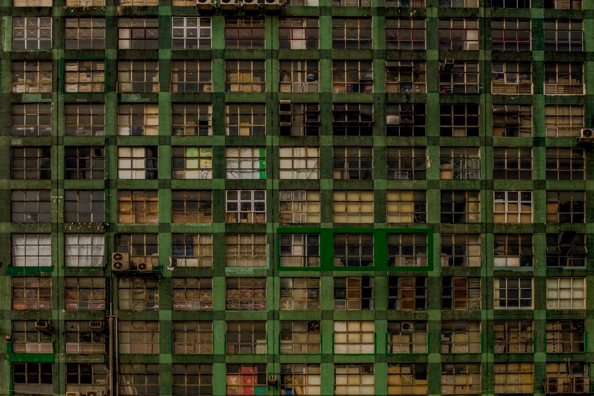 Flat facade of a weathered industrial building with a green-framed window grid