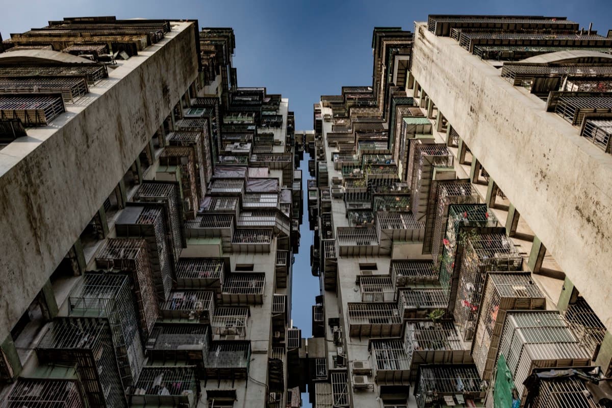 Looking straight up between dense residential tower blocks with balconies and air conditioning units