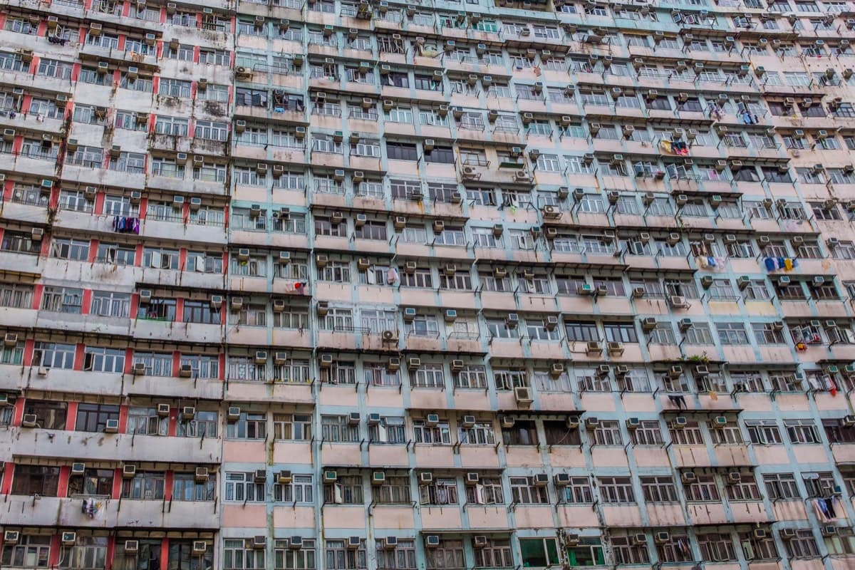Dense residential building facade covered in windows, air conditioning units, and laundry in Quarry Bay