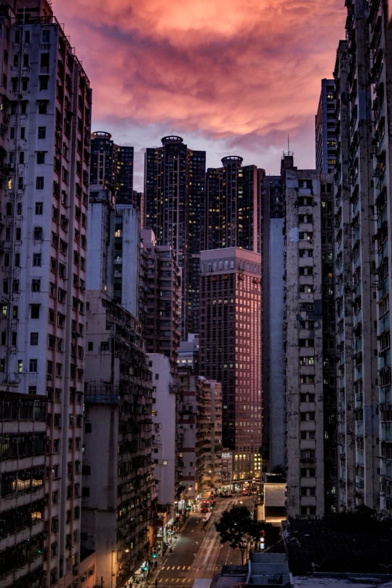 Pink-orange sunset sky framed between dense high-rise residential towers