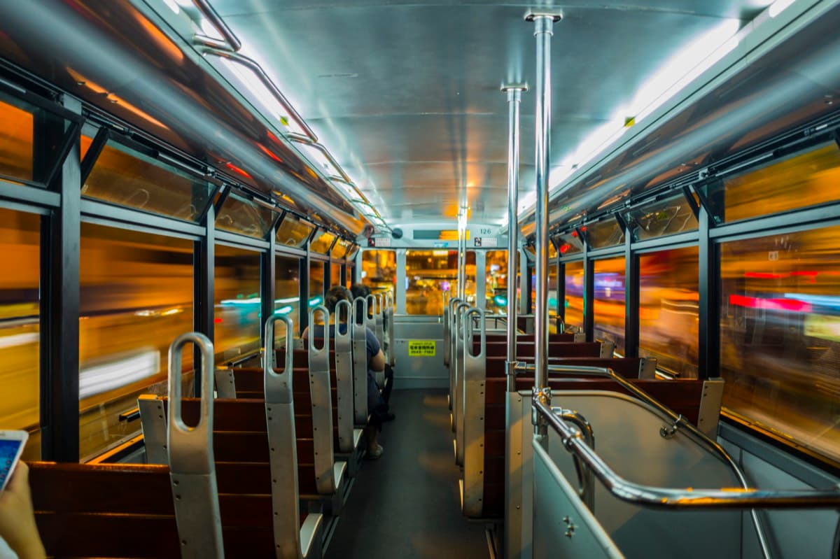 Hong Kong tram upper deck at night with warm motion-blurred lights on both sides